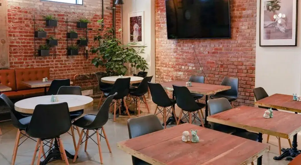 Dining room with red brick walls and wooden tables at Ruby Café MTL
